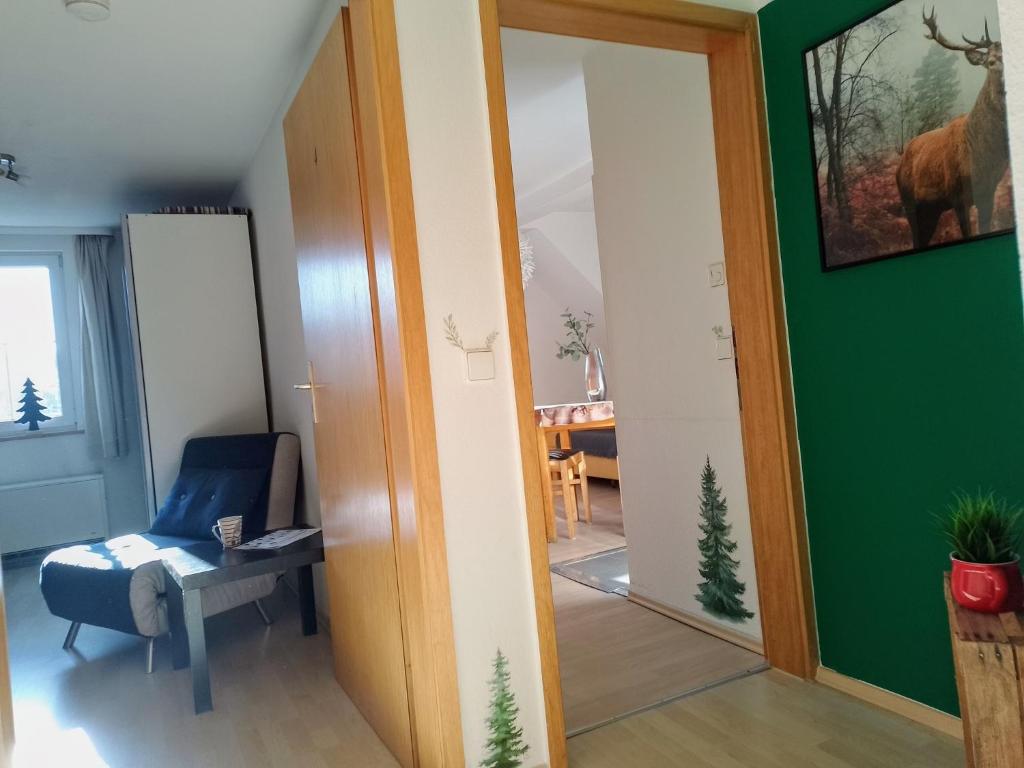 a room with a green wall and a chair and a mirror at Ferienwohnung Waldrausch in Baiersbronn