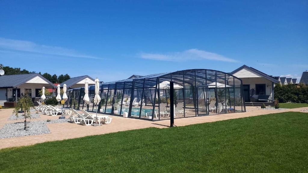 a glass house with a swimming pool in a park at Ośrodek Wypoczynkowy Lawendowo in Jarosławiec