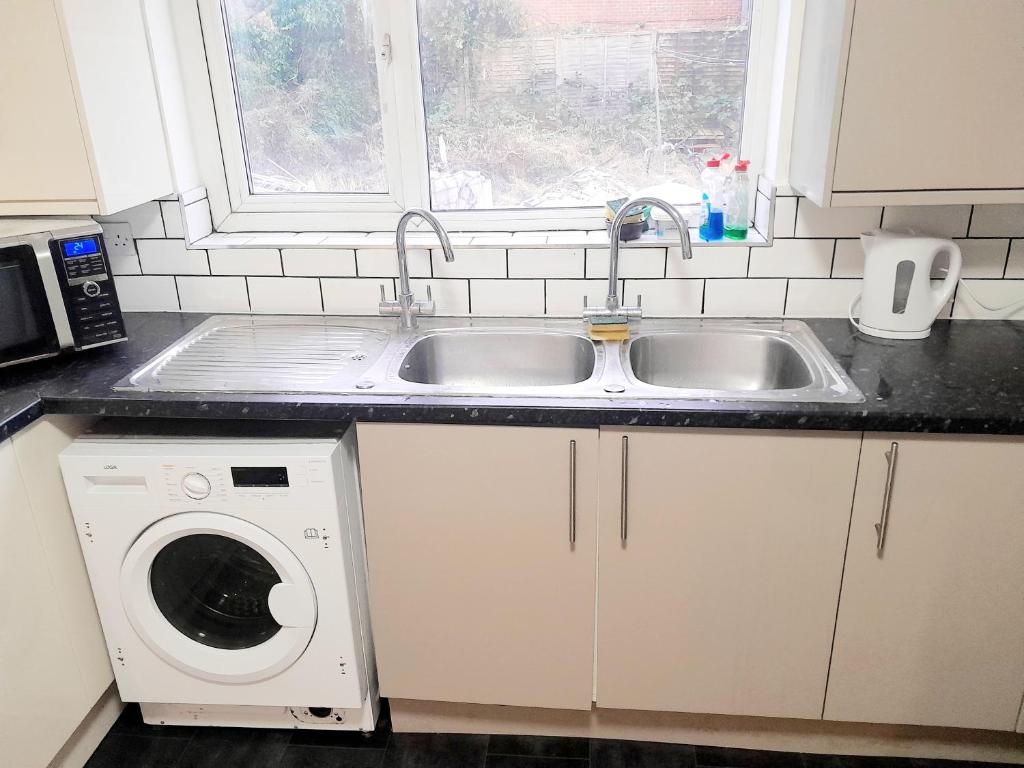a kitchen with a sink and a washing machine at Double ensuite room in Leicester