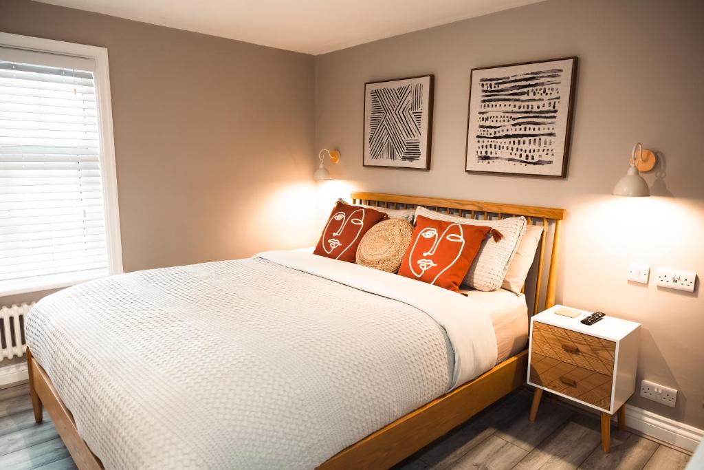 a bedroom with a bed with orange pillows at The Rambler's Rest Cottage, Parkgate, Wirral in Parkgate