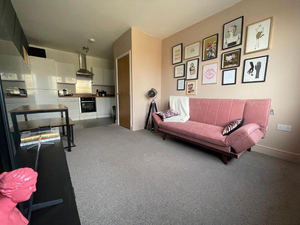 Electra house في سويندون: غرفة معيشة مع أريكة وردية وصور على الحائط