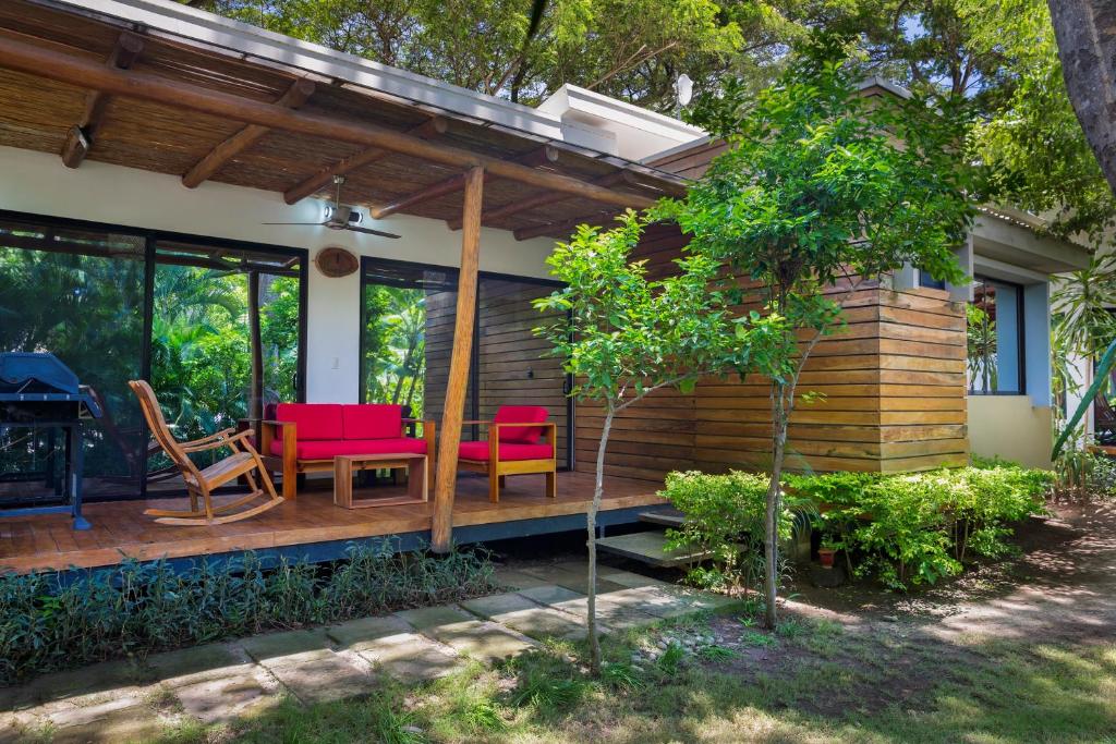 a house with a wooden deck with red chairs at Casa Papaya - Eco Casita Phase 1-1 in Iguana