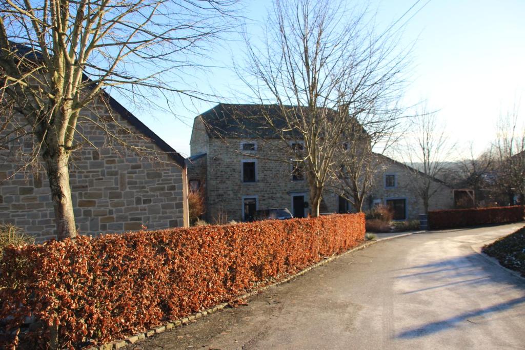 a brick fence next to a house and a building at Prim'tout in Ohey