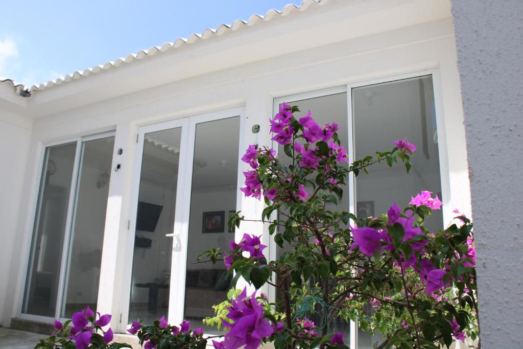 a white house with purple flowers in front of it at CasaMuyuyo - Hermosa Casa de Playa a 1h20 de Guayaquil in Playas
