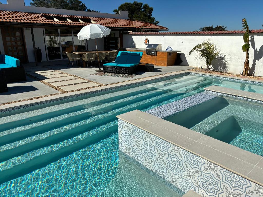 a swimming pool with blue chairs next to a house at Private Hacienda with Heated Pool and Spa with Amazing Views in Del Mar
