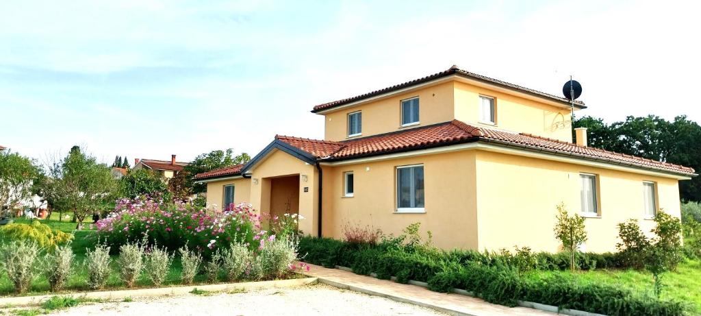 a house with a garden in front of it at Vila Dubravka - lijepa i komforna u zelenilu maslenika i vinograda s jakuzzijem in Valtura