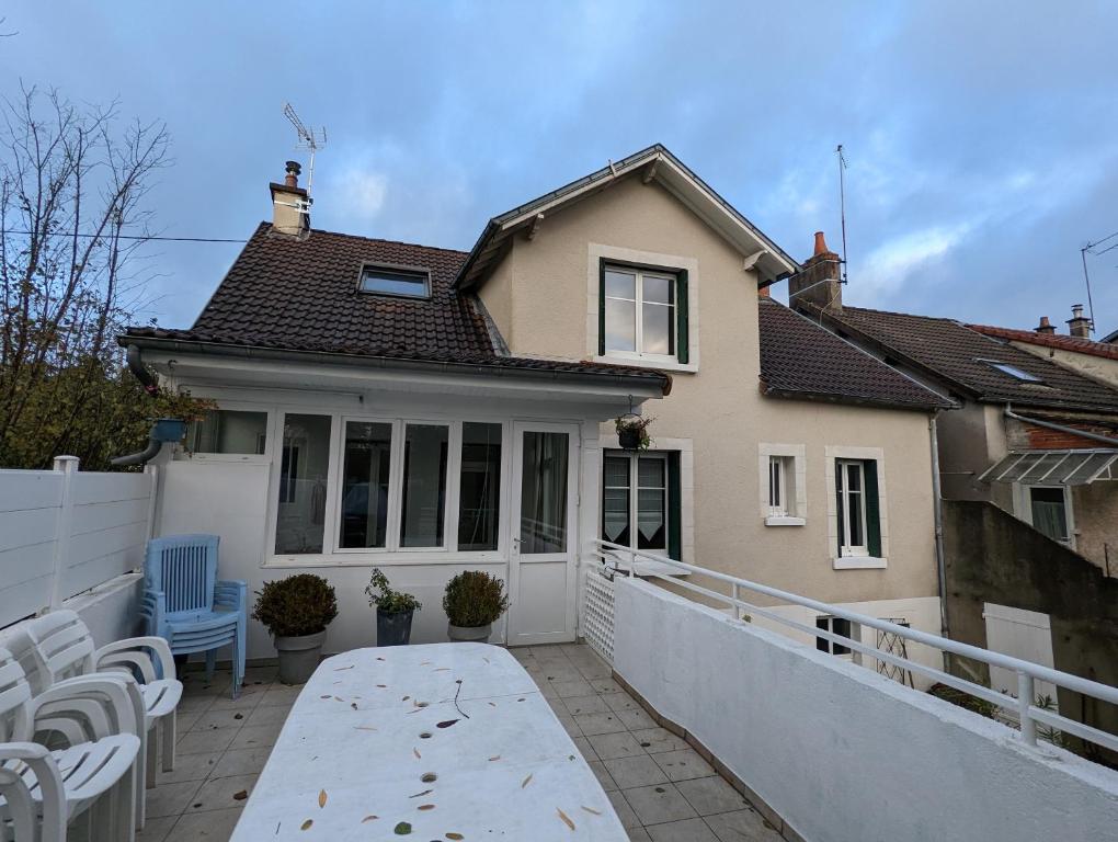 ein Haus mit einem weißen Zaun und Stühlen auf einer Terrasse in der Unterkunft Grande maison avec extérieur, jacuzzi et billard in Vierzon