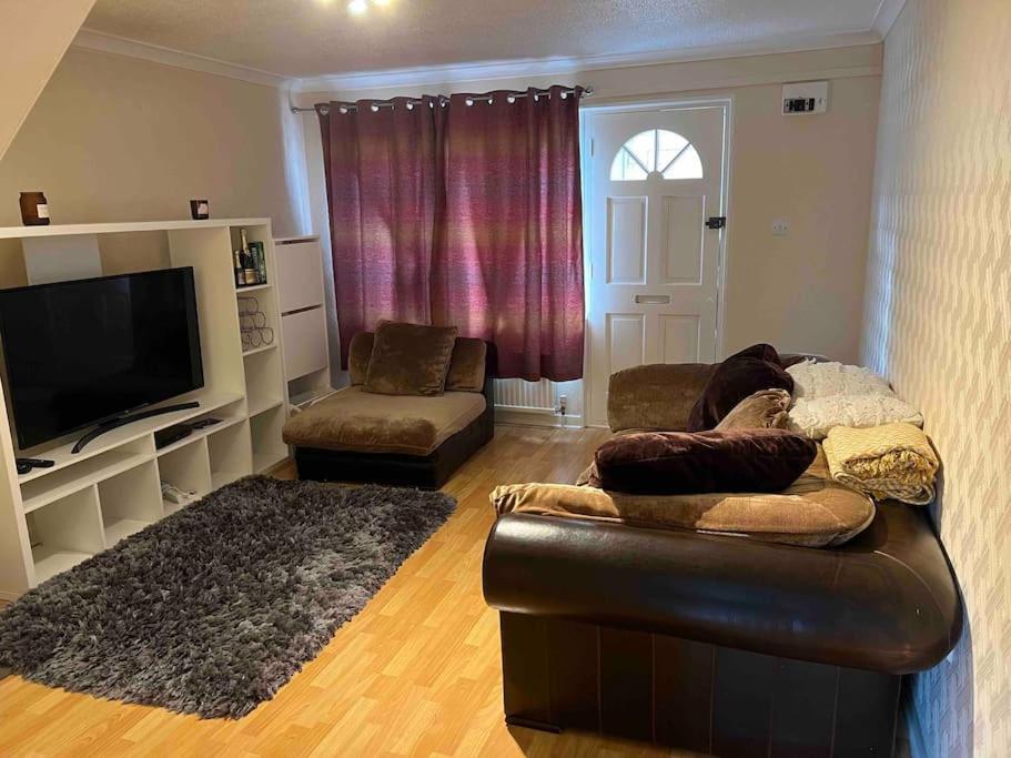 a living room with a leather couch and a television at MK City Center House* 2 bed in Milton Keynes