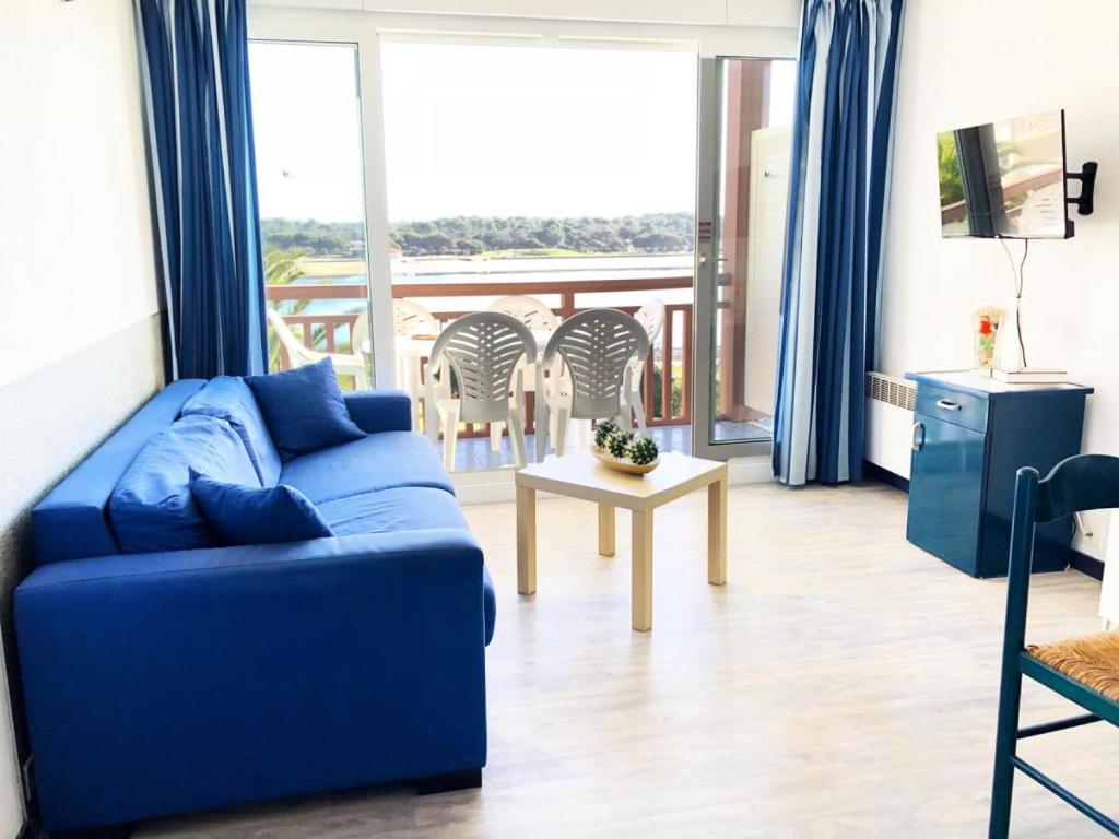 salon z niebieską kanapą i balkonem w obiekcie Résidence Le Boucanier - 3 Pièces pour 6 Personnes 904 w mieście Vieux-Boucau-les-Bains