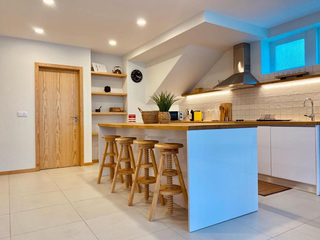 cocina con armarios azules y barra con taburetes en Penagoda Beach House, en Espinho