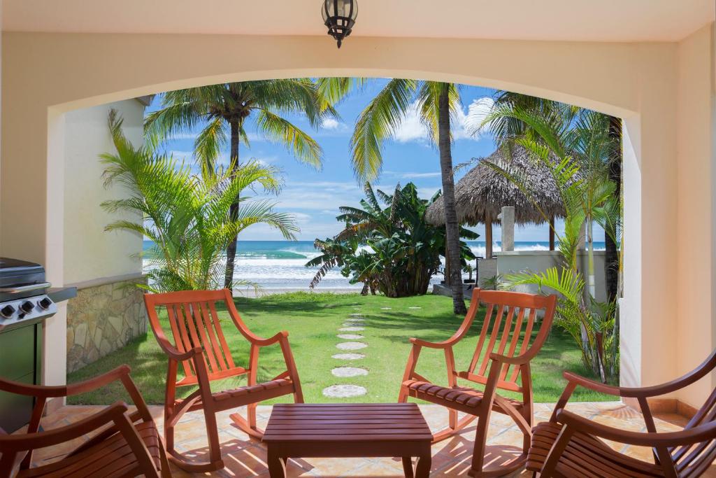 eine Terrasse mit Stühlen, einem Tisch und Meerblick in der Unterkunft Villas Iguana A-13 Beachfront Condo in Iguana