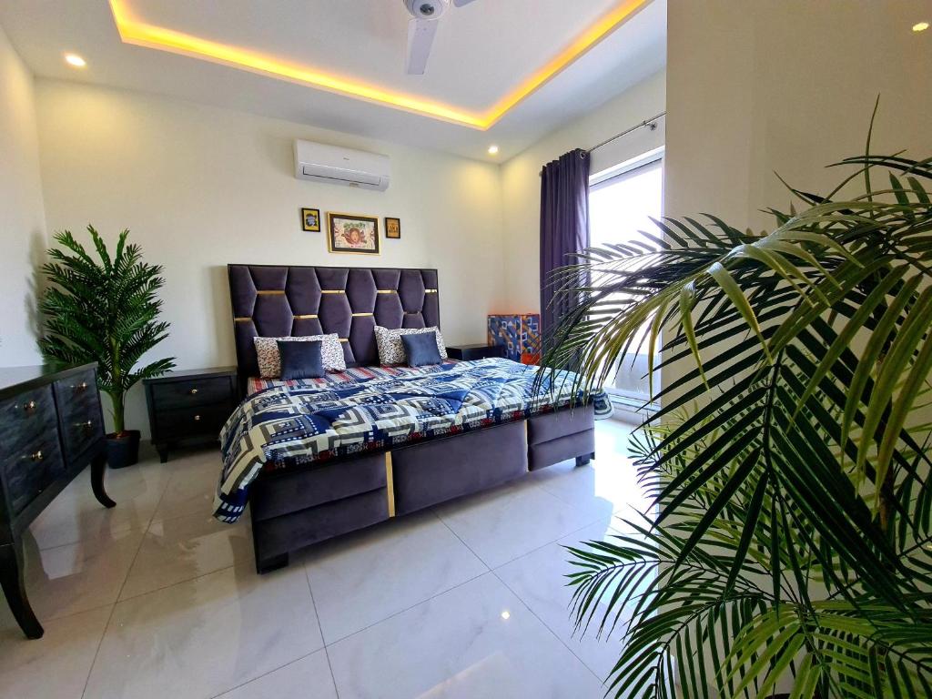 sypialnia z łóżkiem i dużą rośliną w obiekcie 1 Bed Modern Apartment, Pool, Gym, Cinema w mieście Lahaur