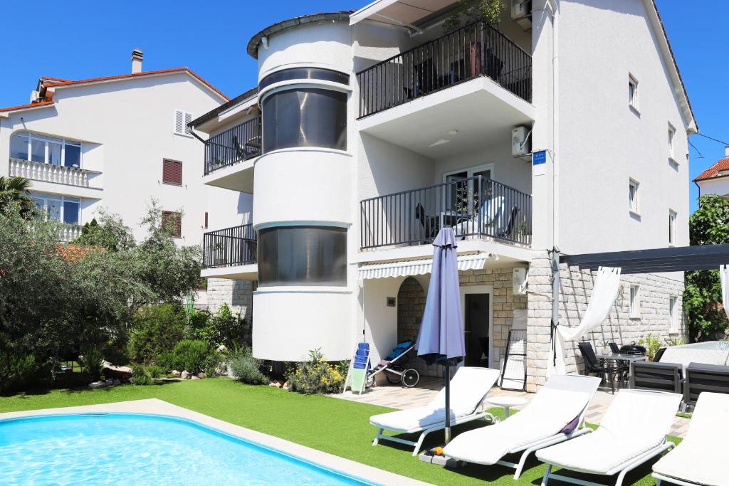 a villa with a swimming pool in front of a building at Apartments Skandi1 in Malinska