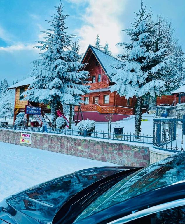 una casa con alberi coperti di neve di fronte ad essa di Planinska kuća Mali Raj a Mrkonjić Grad