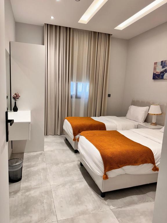 a hotel room with two beds and a desk at شقة مودرن 3غرف نوم وصاله بالملقا c in Riyadh