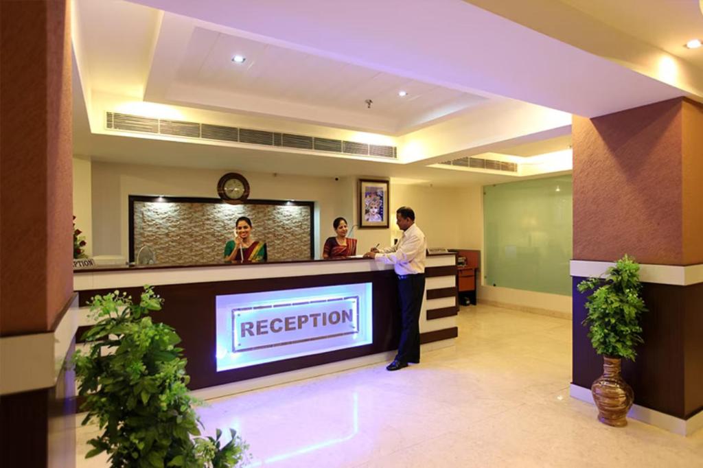 a man standing at a reception desk in a lobby at Hotel Impress Delhi Airport in New Delhi