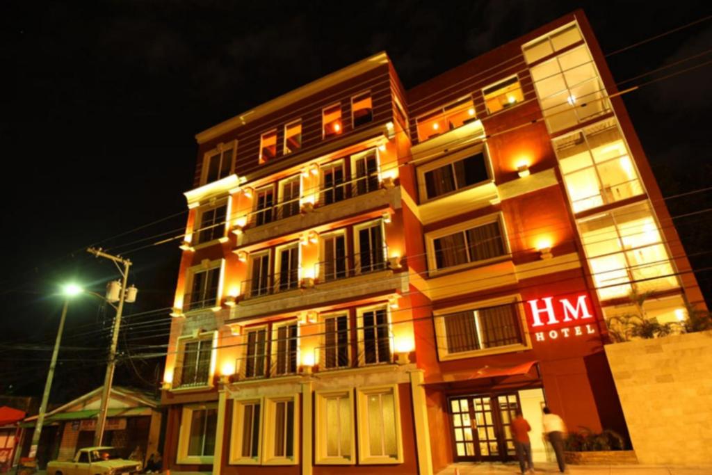 Um edifício iluminado com um homem à frente dele. em Hotel Martell em San Pedro Sula