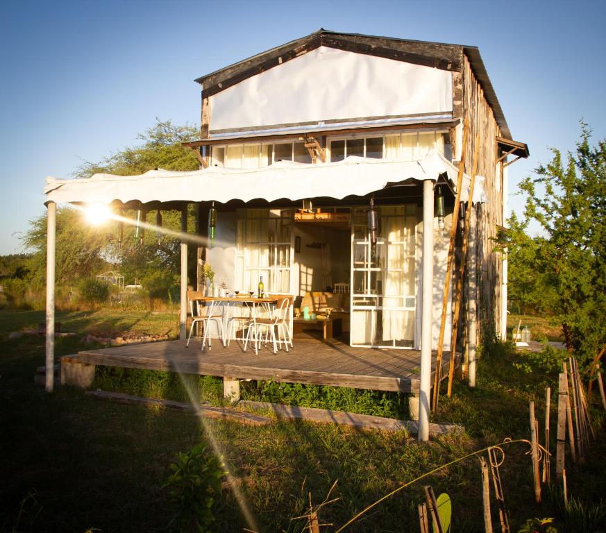 a house with a deck with a table and chairs at Uy - Cabaña de ESTILO, entorno Natural ùnico in Mercedes