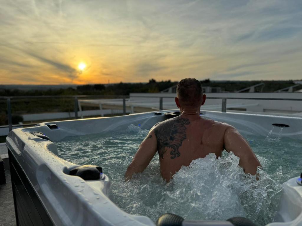 a man in a jacuzzi tub with the sunset at WHITE HOUSE EN ENGUERA - Fantástica casa con jacuzzi piscina y barbacoa in Enguera