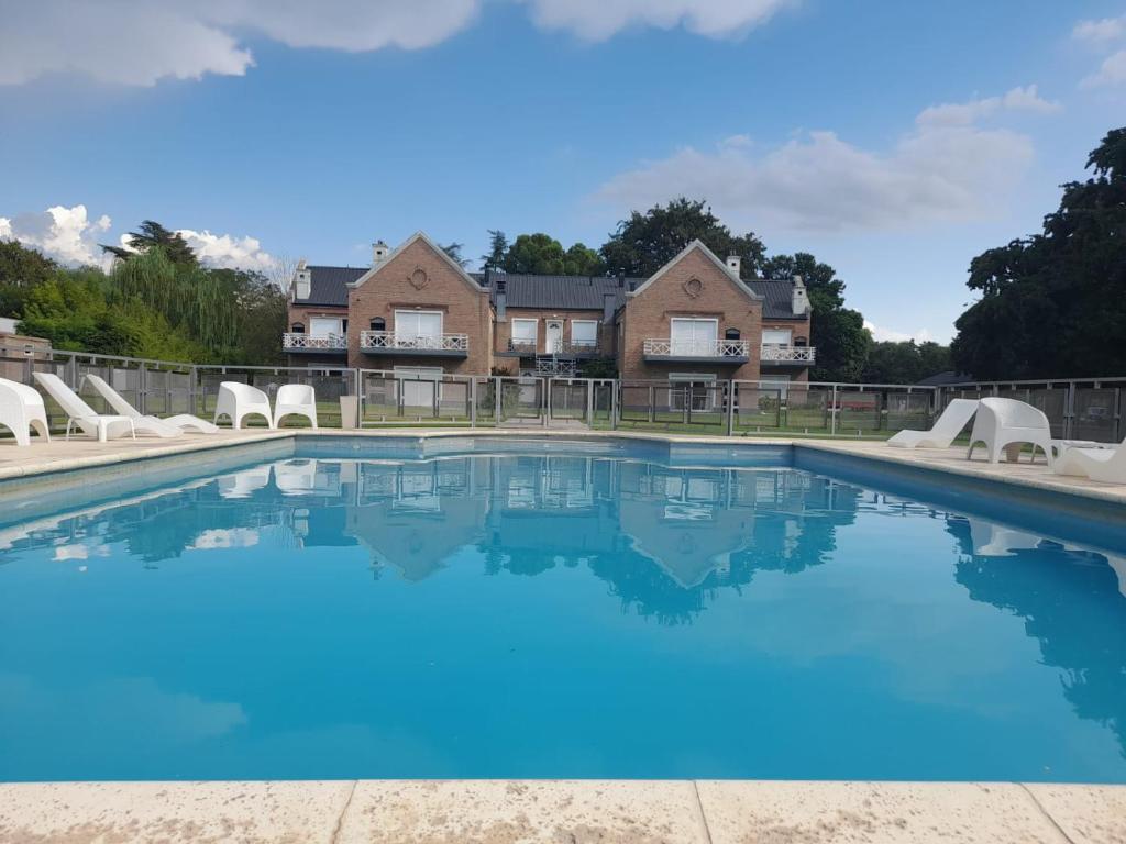 a pool with blue water in front of a house at Los Robles Apart Hotel in Sierra de la Ventana