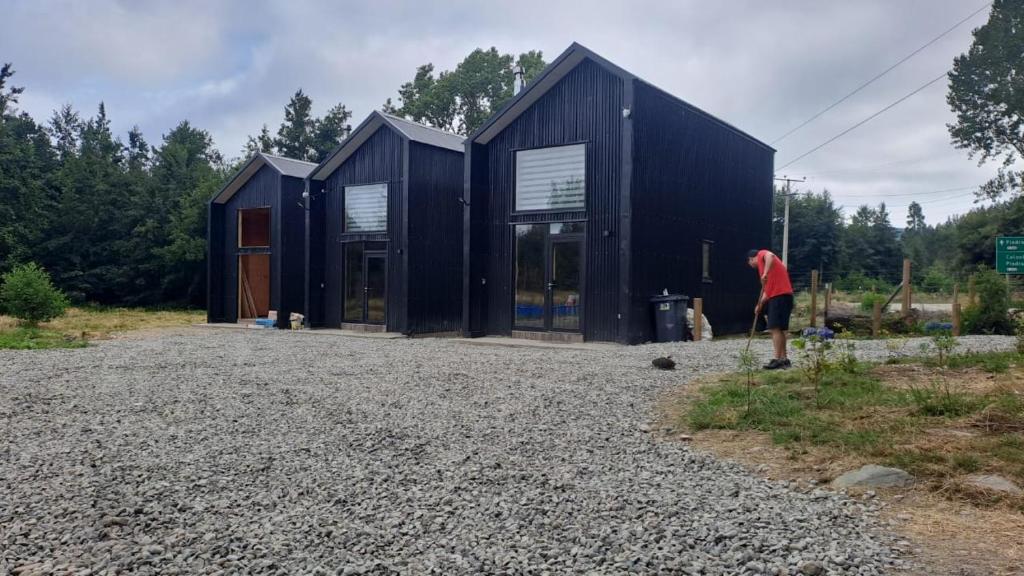 eine Person, die vor einem schwarzen Haus steht in der Unterkunft Cabaña Valdivia Piedra Blanca 2 in Valdivia