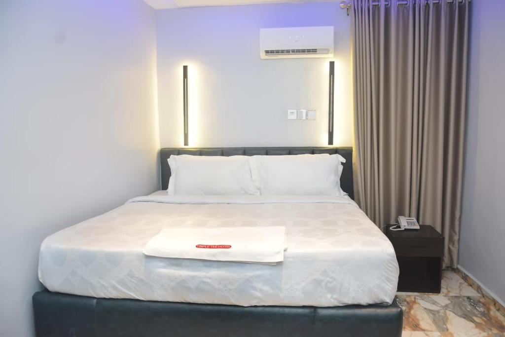 a bed with a white blanket and a towel on it at Triple Tee Luxury Hotel & Service Apartments Surulere in Lagos
