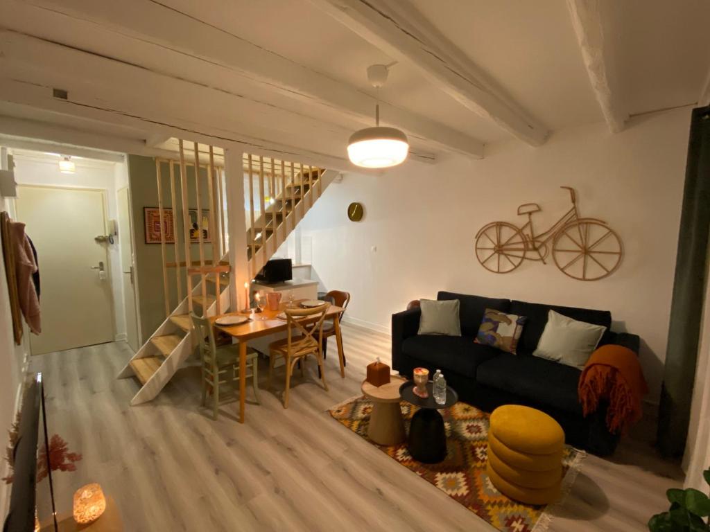 ein Wohnzimmer mit einem schwarzen Sofa und einem Tisch in der Unterkunft A22 - Les Cosy De Nancy - Le bohème chic 4* in Nancy