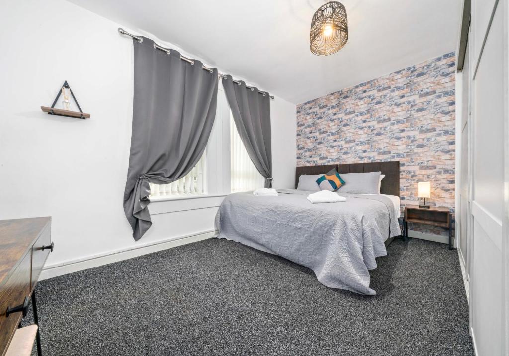ein Schlafzimmer mit einem Bett und einer Ziegelwand in der Unterkunft Lady Wilson Apartment by Klass Living Airdrie in Airdrie