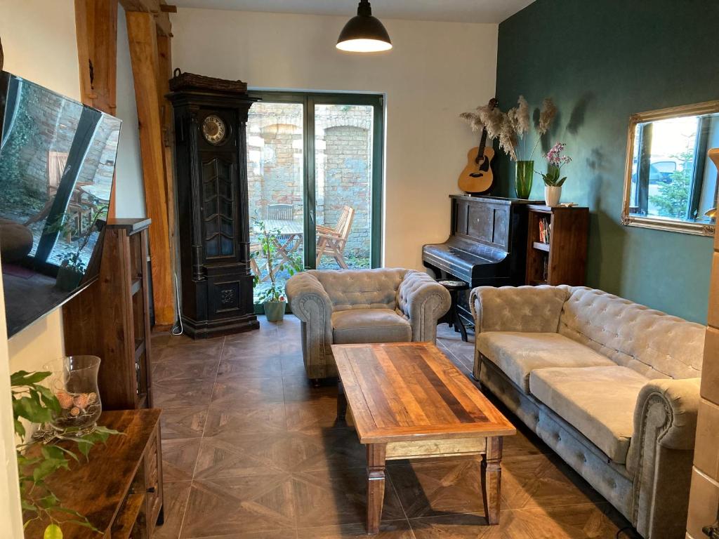 uma sala de estar com um sofá, uma mesa e um piano em Ferienwohnung Rübezahl em Waren