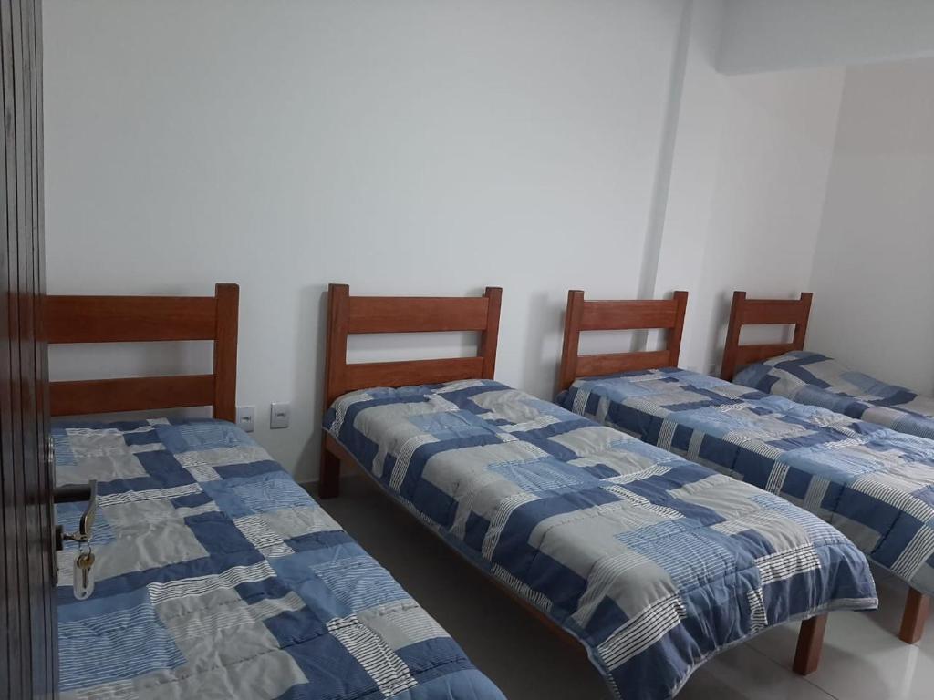 três camas num quarto com cobertores azuis e brancos em Thiferer Hostel em Viçosa