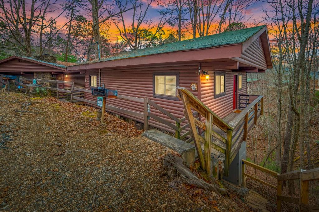 a cabin in the woods with a sunset in the background at Laughing Bear Cabin 44B in Bryson City