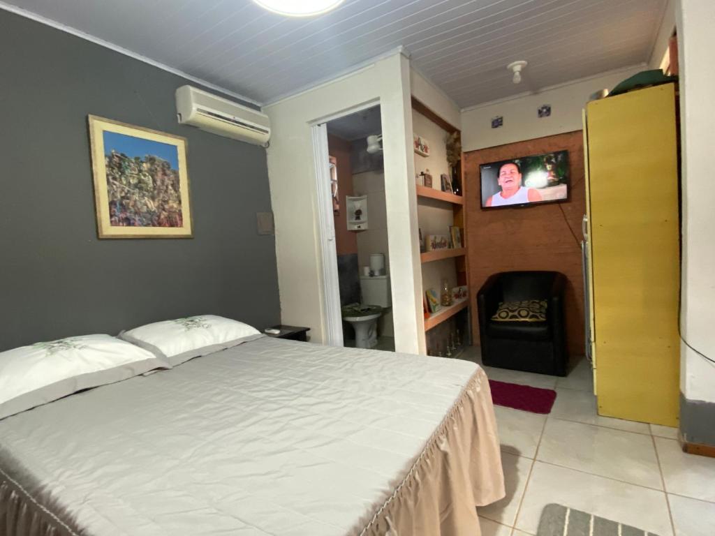 a bedroom with a bed and a tv on a wall at Espaço privativo, funcional e aconchegante in Santana do Livramento