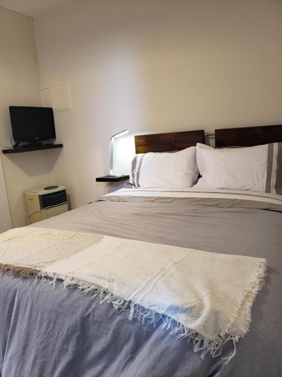1 dormitorio con 1 cama grande con sábanas blancas y TV en Centric, private, petfriendly apartments in Miraflores, en Lima