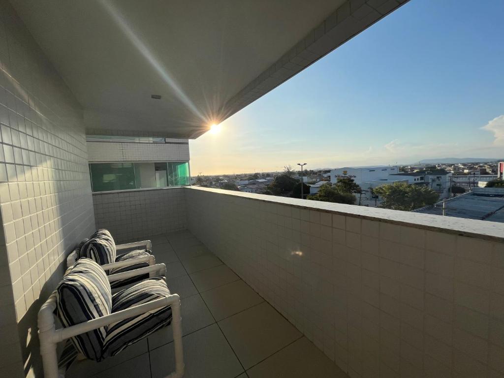 a balcony with three chairs and a view of the city at Village blue AC Wi-Fi piscina in Cabo Frio