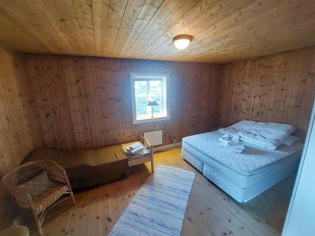 a bedroom with a bed and a chair and a window at Valen Cabins in Reine in Reine