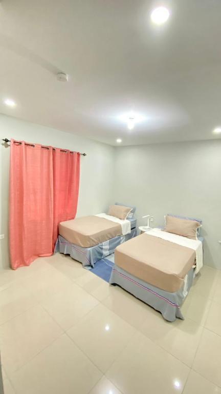 Habitación con 2 camas y cortina roja. en Serenity Condo, en Piarco