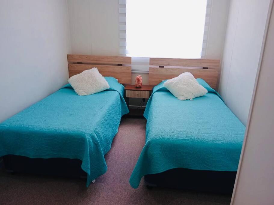 2 camas en una habitación pequeña con ventana en Casa Aloe Villarrica con Aire Acondicionado, en Villarrica