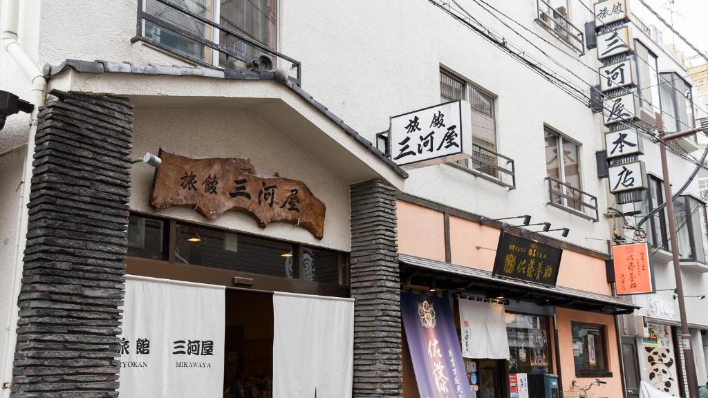 un negozio con un cartello sul lato di un edificio di Ryokan Mikawaya a Tokyo