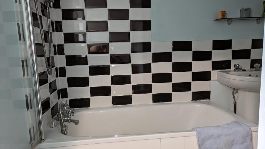 a bathroom with a bath tub and a checkered wall at Southsea in Coedpoeth