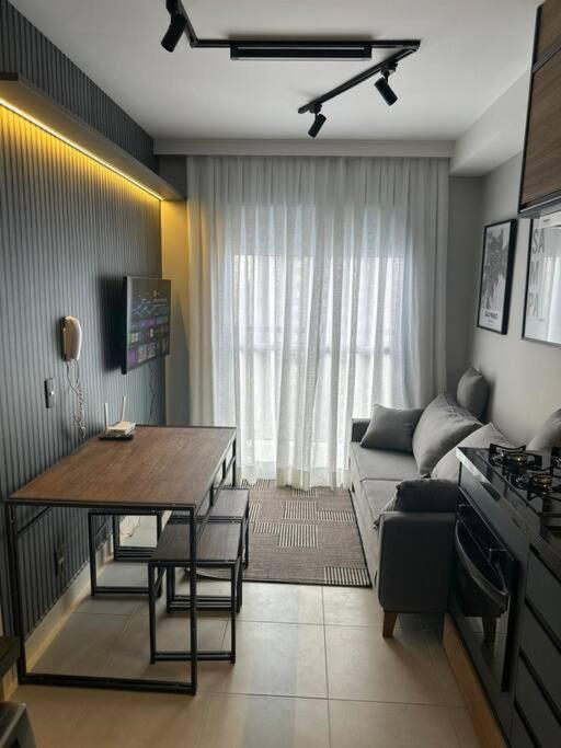 cocina y sala de estar con mesa y sofá en Belo Studio com suíte e varanda en São Paulo