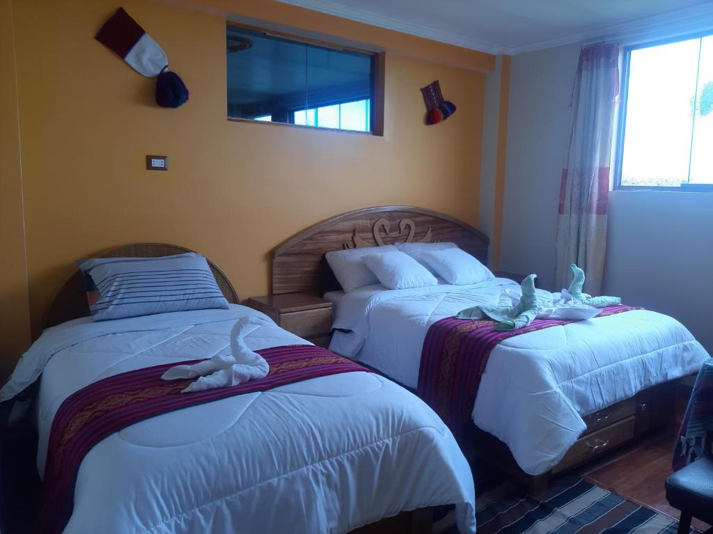 a bedroom with two beds with stuffed animals on them at Taquile Inti Raymi Lodge in Huillanopampa