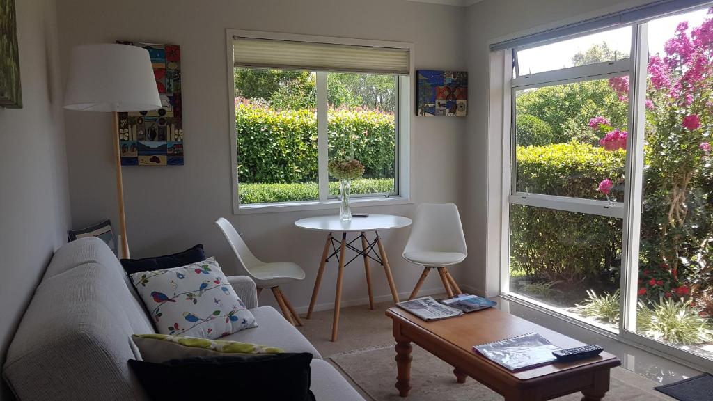 a living room with a couch and a table and two windows at Mangawhai Heads apartment in Mangawhai