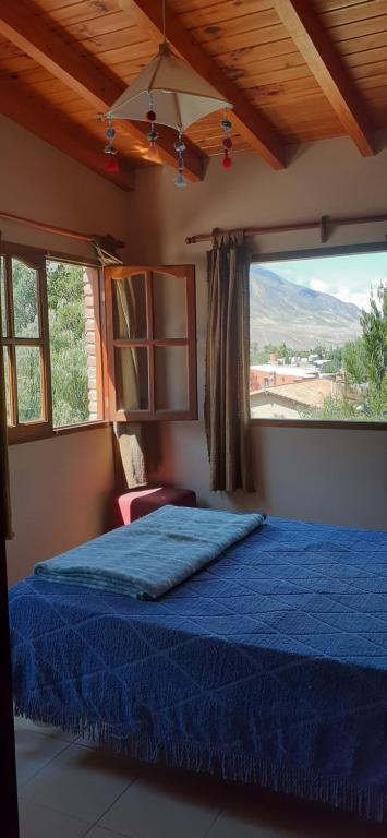 1 dormitorio con cama azul y ventana grande en Maimará Jujuy en Maimará