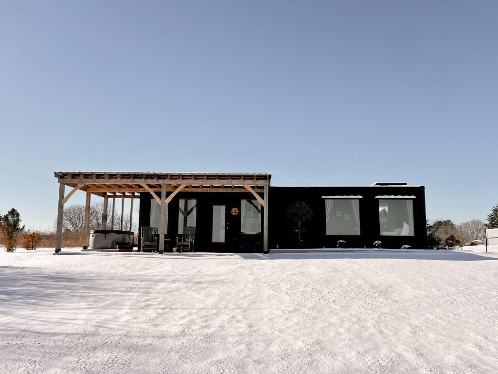 ein schwarzes Gebäude mit Markise auf einem schneebedeckten Feld in der Unterkunft Charming Container Getaway Amidst Rural Serenity in Pine Grove