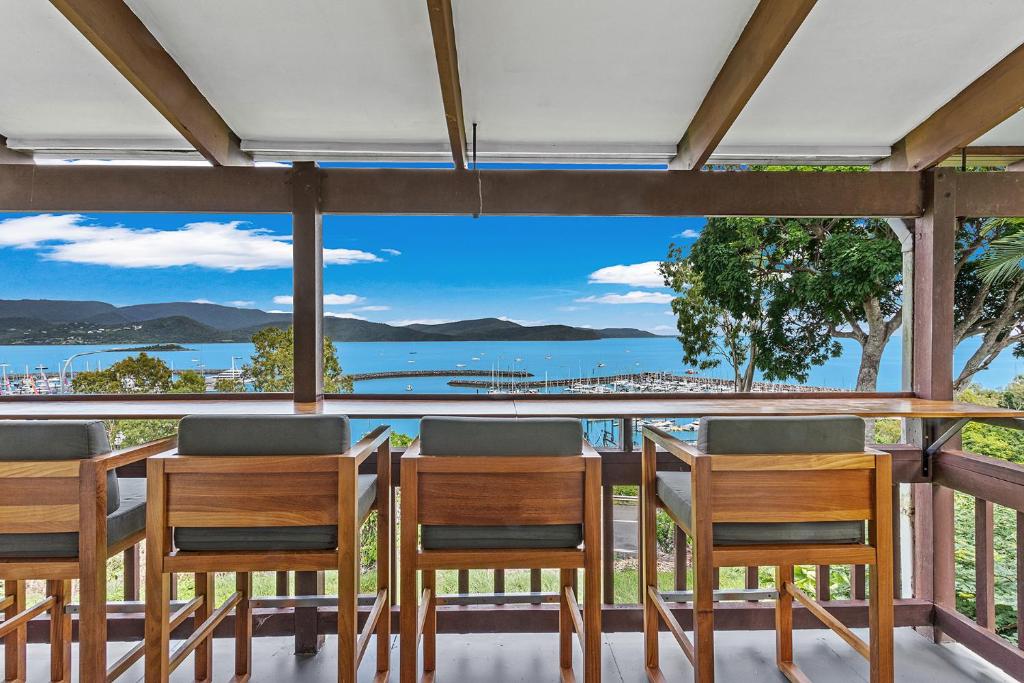 a table and chairs on a balcony with a view of the water at Sailor's Lookout in Airlie Beach