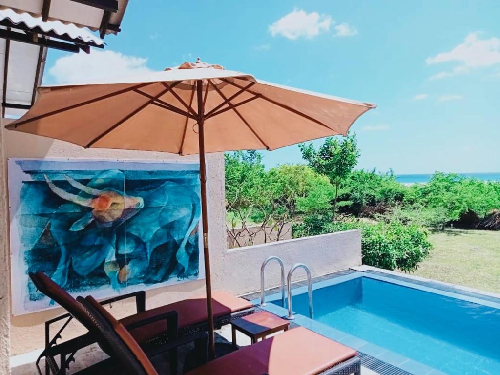 an umbrella and chairs next to a swimming pool at C Beyond Nilaveli in Nilaveli