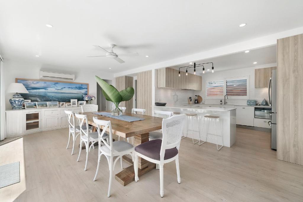 uma cozinha com uma mesa de madeira e cadeiras brancas em 5BR Mermaid Waters Luxury Home em Gold Coast