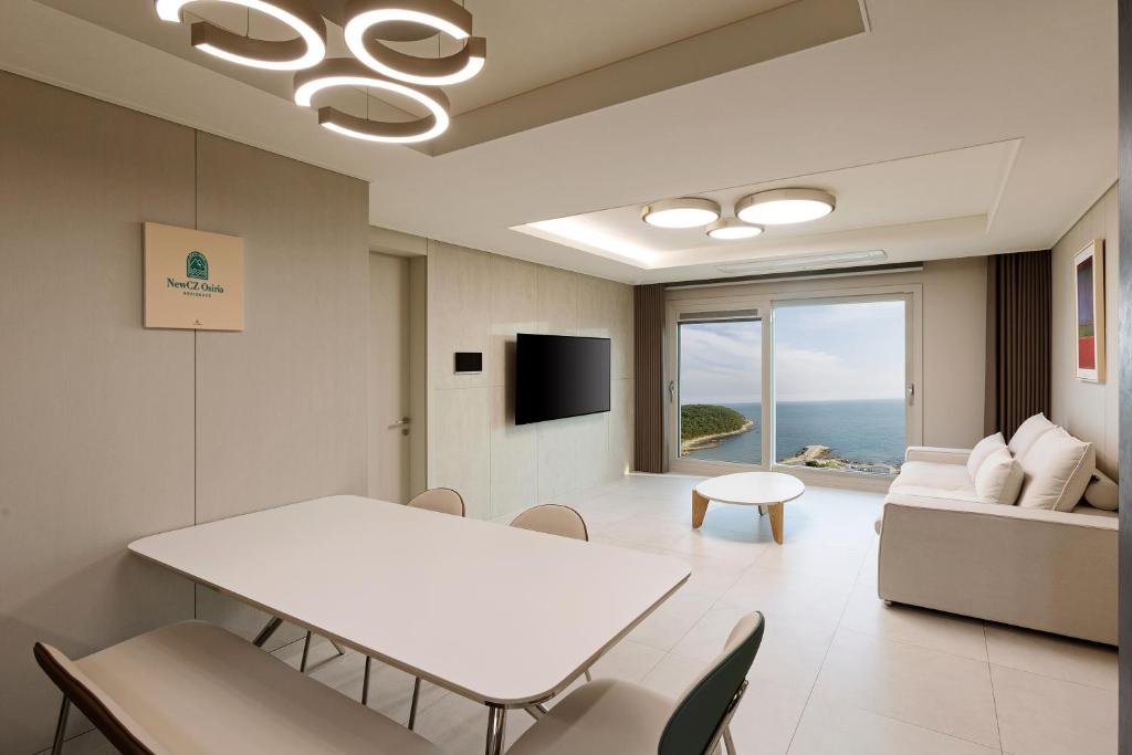 NewCZ Osiria Residence في بوسان: غرفة معيشة مع طاولة وكراسي بيضاء