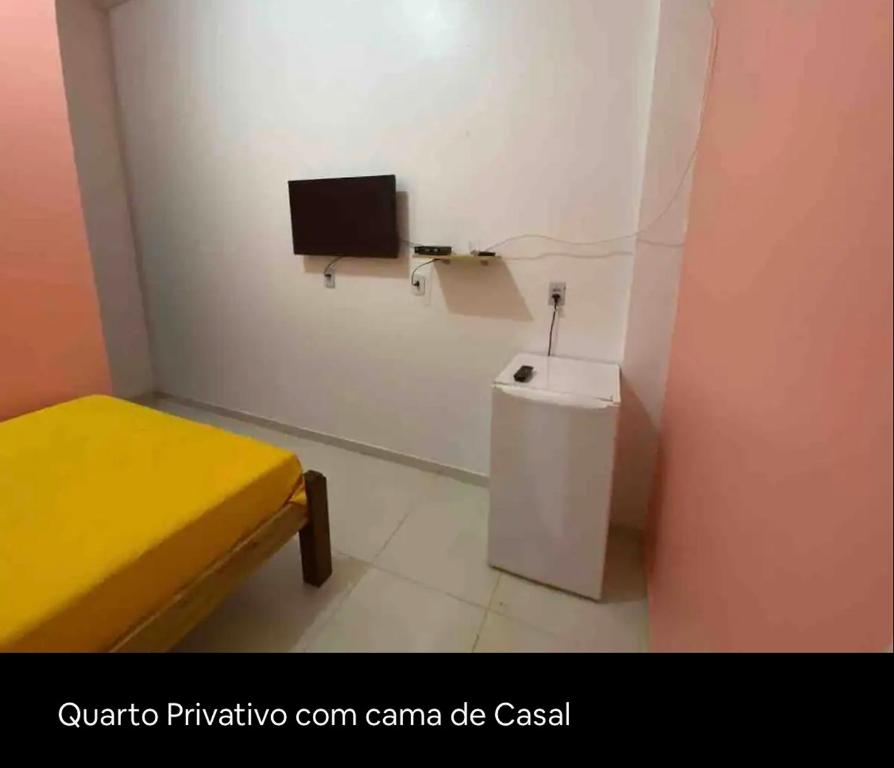 Habitación pequeña con aseo y TV en la pared. en Hotel Divino en Alvarães