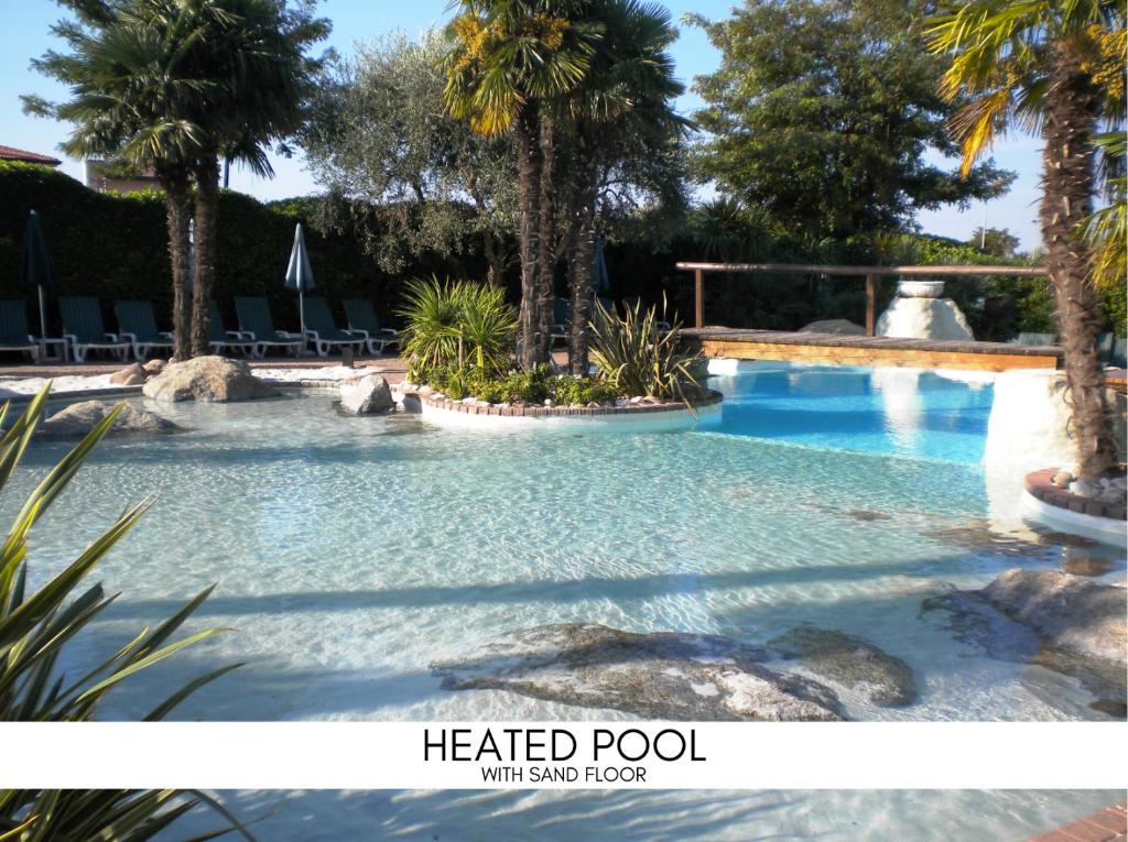 einen Pool mit Palmen in einem Resort in der Unterkunft Palazzo della Scala Spa Hotel Suites & Apartments in Lazise